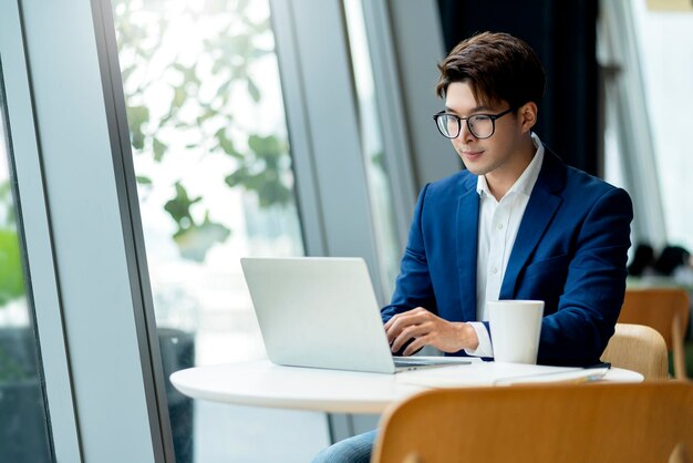 Intelligente, attraktive, positive asiatische Geschäftsmänner, die eine Brille tragen, arbeiten entfernt, neuer normaler Lebensstil, Handgebrauch, Laptop-Telekonferenz, Onlive-Videoanruf, Treffen, entferntes Geschäftsideenkonzept