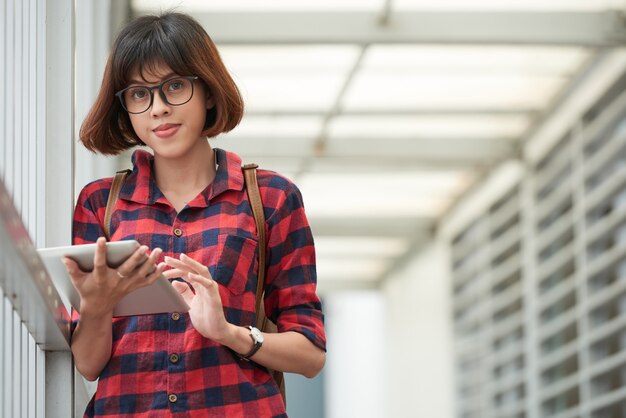 Intelligenter Student mit Brille, der mobile App auf der digitalen Auflage verwendet