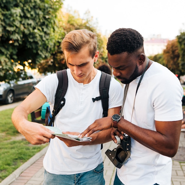 Interkulturelle Freunde, die zusammen Karte lesen