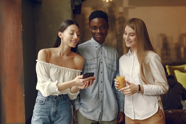 Internationale Leute, die in einem Café mit Handy stehen