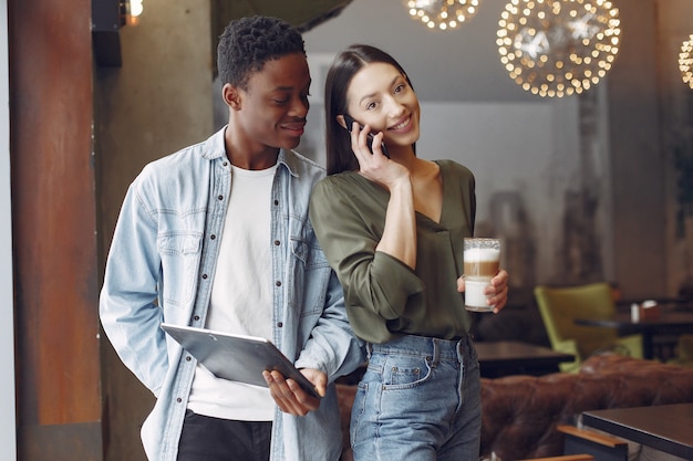 Internationale Leute, die in einem Café mit Tablette und Kaffee stehen