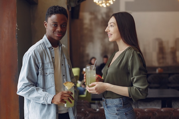 Internationale Leute, die in einem Café stehen und Cocktails trinken