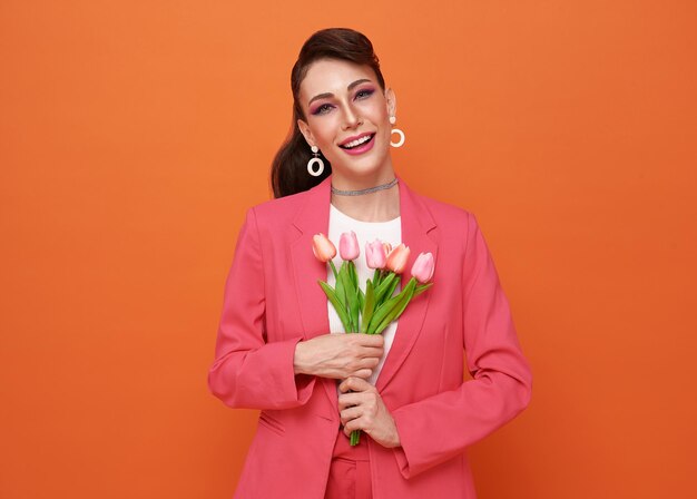 Internationaler frauentag glückliche frau in rosafarbenem blazer mit tulpenstrauß auf orangefarbenem hintergrund