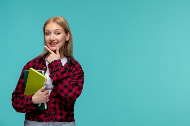 Internationaler Studententag junges süßes Mädchen in rot kariertem Hemd, das Gesicht berührt und Bücher hält