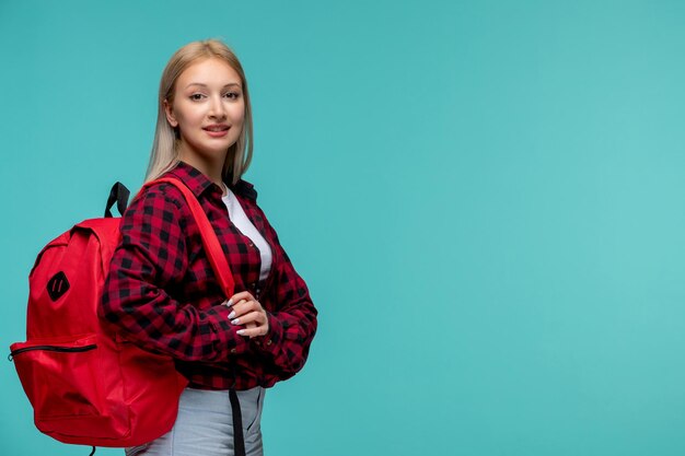 Internationaler Studententag süßes hübsches Mädchen in rot kariertem Hemd lächelnd mit rotem Rucksack