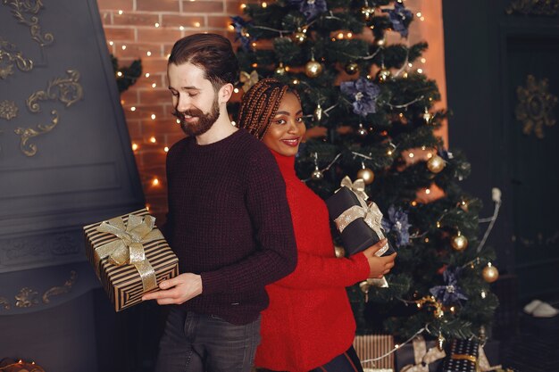 Internetionale Menschen zu Hause. Paar in einer Weihnachtsdekoration. Afrikanische Frau und kaukasischer Mann.