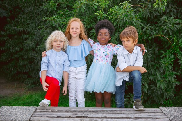 Interracial-Gruppe von Kindern, Mädchen und Jungen, die am Sommertag zusammen im Park spielen