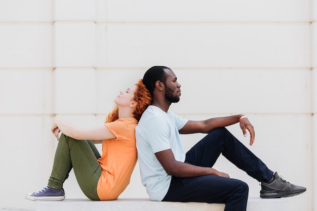 Kostenloses Foto interracial paar rücken an rücken sitzen