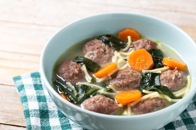 Kostenloses Foto italienische hochzeitssuppe mit fleischbällen und spinat auf einem holztisch.