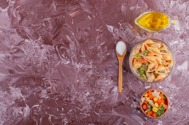 Italienische Muschelnudeln mit Öl und gemischtem Gemüsesalat auf hellem Tisch.