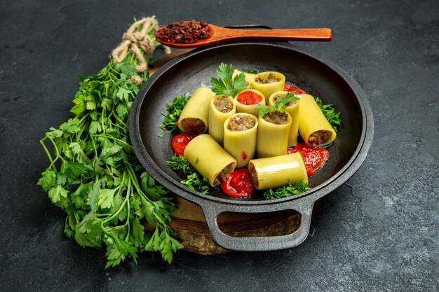 Italienische Nudeln der Vorderansicht mit grüner Tomatensauce und Fleisch innerhalb der Pfanne auf grauer Stelle