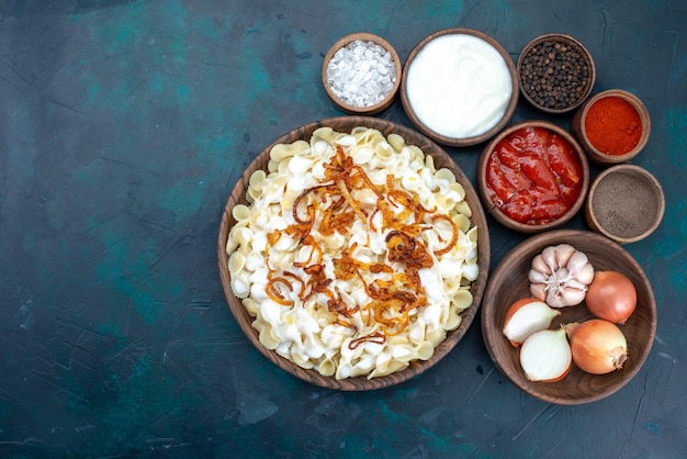 Italienische Pasta von oben mit verschiedenen Gewürzen im Dunkeln