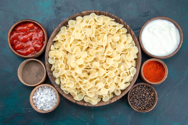 Italienische Pasta von oben mit verschiedenen Gewürzen im Dunkeln