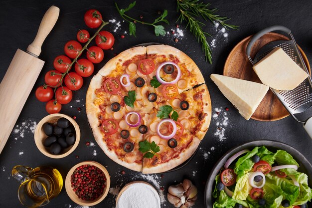 Italienische Pizza und Pizzakochzutaten auf dunkler Steinoberfläche