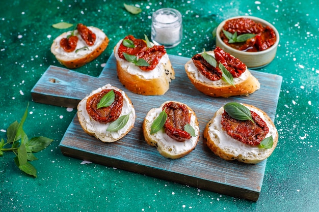 Italienische Sandwiches - Bruschetta mit Käse, trockenen Tomaten und Basilikum.