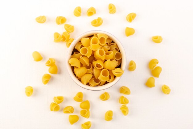 Italienische trockene Nudeln der Draufsicht rohe gelbe Nudeln innerhalb der Schüssel auf dem Weiß