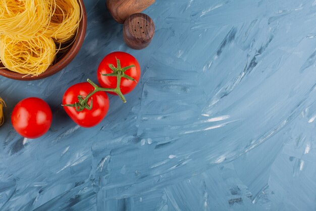 Italienisches Nudel-Fettuccine-Nest mit frischen roten Tomaten und Gewürzen.