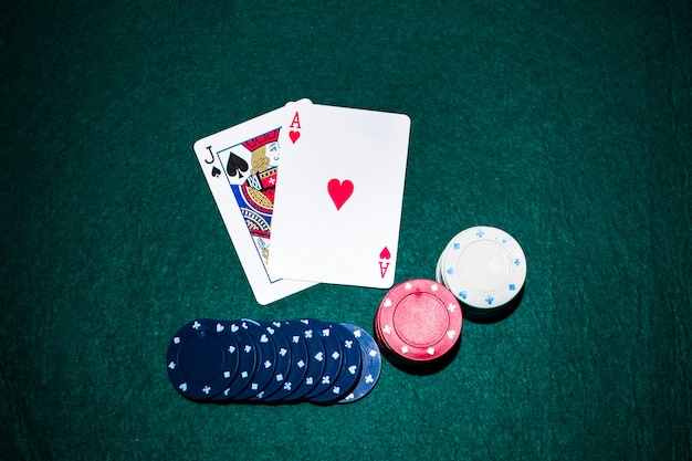 Jack der Spaten- und Herzasskarte mit Kasinochips stapeln auf grüner Pokertabelle