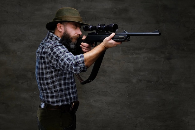 Kostenloses Foto jäger, der mit einem gewehr in sichtweite zielt, während er sich darauf vorbereitet, einen genauen schuss auf die beute abzugeben. getrennt auf einem dunklen hintergrund.