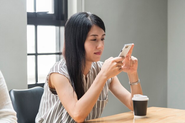 Japanische Frau, die an ihrem Telefon spielt