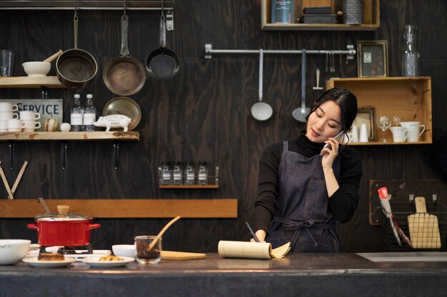 Japanische Frau, die in einem Restaurant mit dem Smartphone spricht