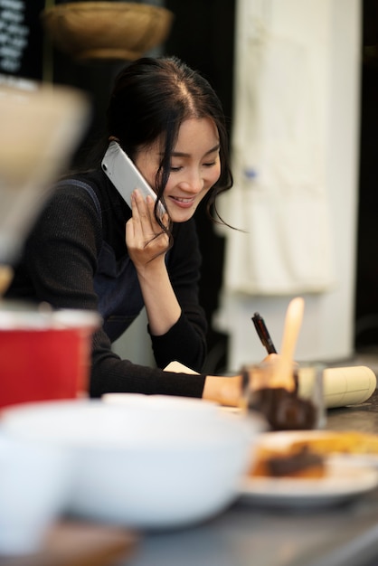 Japanische Frau, die in einem Restaurant mit dem Smartphone spricht