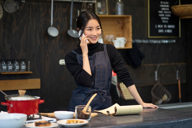 Japanische Frau, die in einem Restaurant mit dem Smartphone spricht