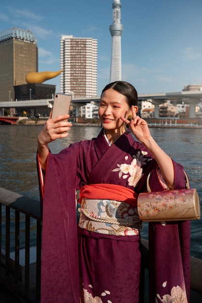 Kostenloses Foto japanische frau feiert den tag des erwachsenwerdens und macht selfie im freien