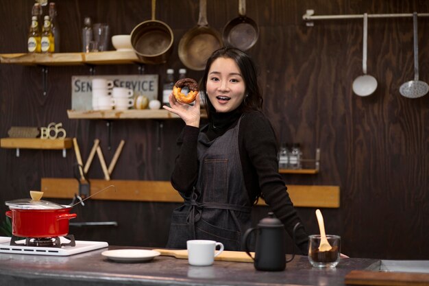 Japanische Frau posiert, während sie einen Donut hält