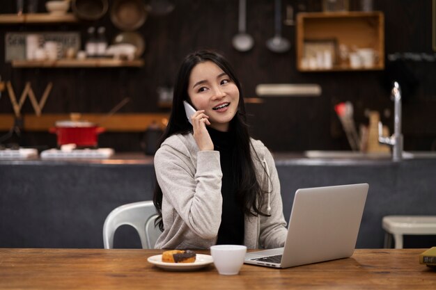 Japanische Frau spricht auf ihrem Smartphone, während sie in einem Restaurant arbeitet