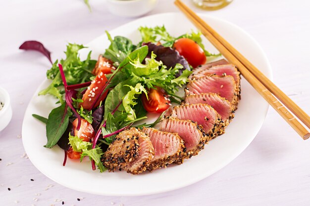 Japanischer traditioneller Salat mit Stücken von mittel-seltenem gegrilltem Ahi-Thunfisch und Sesam mit frischem Gemüsesalat auf einem Teller.