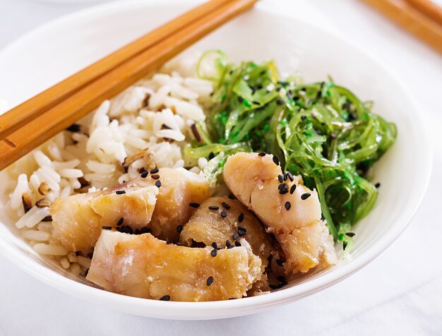 Japanisches Essen. Schüssel Reis, gekochter Weißfisch und Wakame Chuka oder Algensalat.