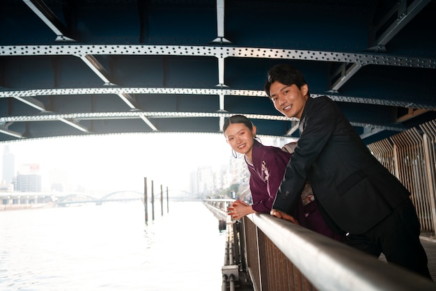 Kostenloses Foto japanisches paar posiert an der brücke und feiert den tag der volljährigkeit