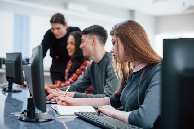 Jeder macht seine Arbeit. Gruppe junger Leute in Freizeitkleidung im modernen Büro