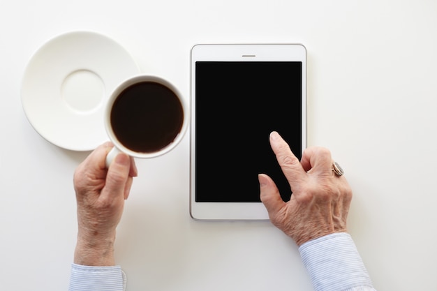 Jemand benutzt das Touchpad, während er eine Tasse Kaffee trinkt