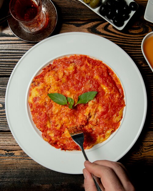 Jemand, der mit Tomaten und Eiern frühstückt