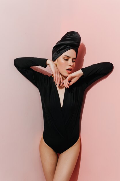 Jocund weibliches Modell, das im schwarzen Turban und im Bodysuit aufwirft