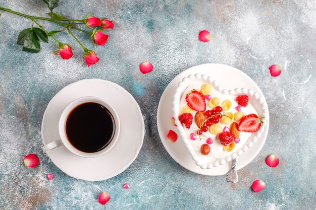 Joghurt mit Cornflakes und Beeren in einer herzförmigen Schüssel.