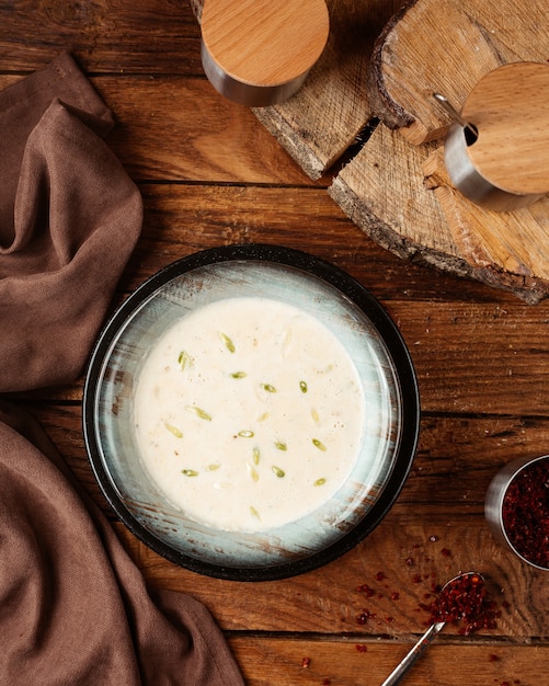 Joghurtsuppe von oben in der schwarzen Platte auf der hölzernen Schreibtischnahrungsmittelsuppe