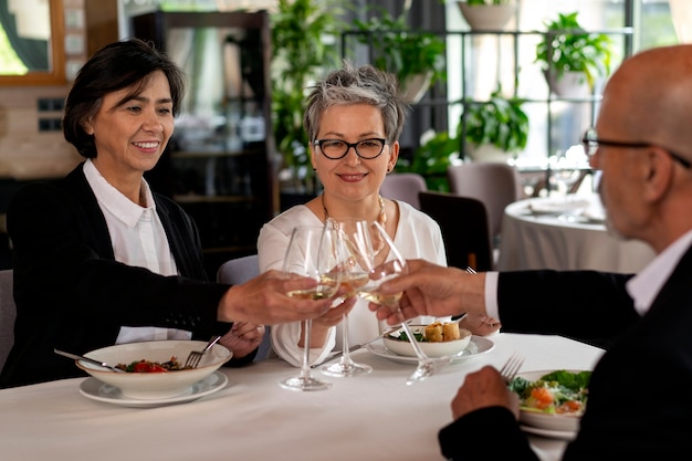 Kostenloses Foto jubelnde menschen mit weingläsern in einem luxuriösen restaurant