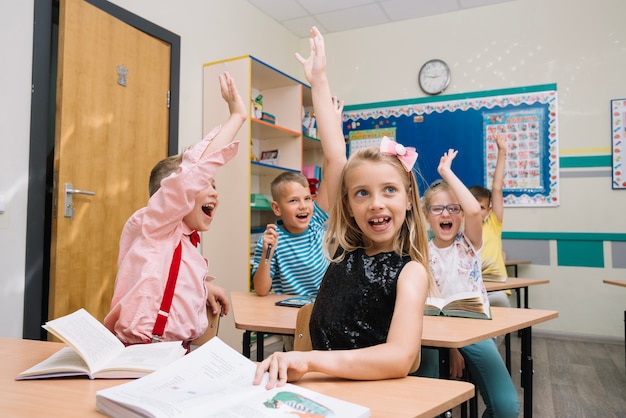 Jubelnde Schulkinder im Klassenzimmer, die Hände heben