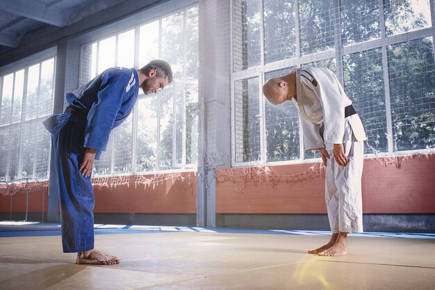 Judo-Kämpfer begrüßen sich in einem Bogen, bevor sie in einem Kampfclub Kampfkunst üben