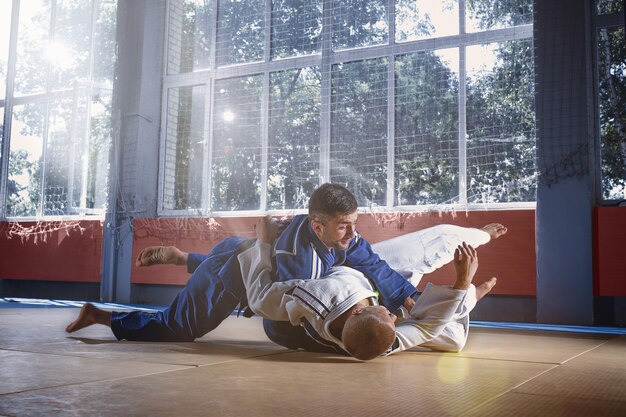 Judo-Kämpfer, die technische Fähigkeiten zeigen, während sie in einem Kampfclub Kampfkunst üben