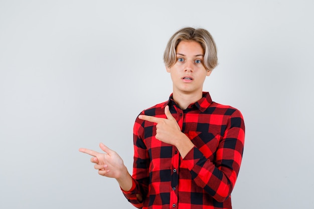 Jugendlich blonder Mann im lässigen Hemd, das nach links zeigt und nachdenklich schaut, Vorderansicht.