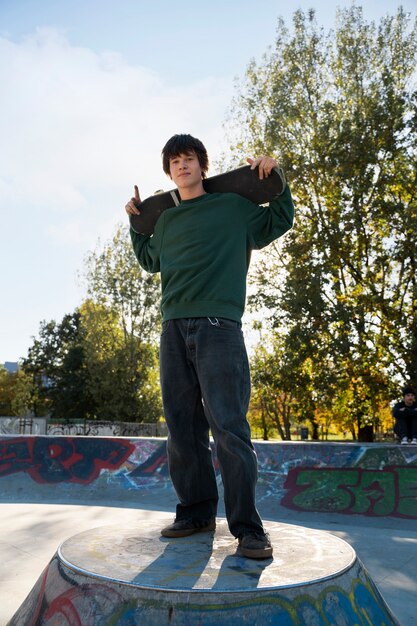 Kostenloses Foto jugendlich haltenes skateboard der vorderansicht
