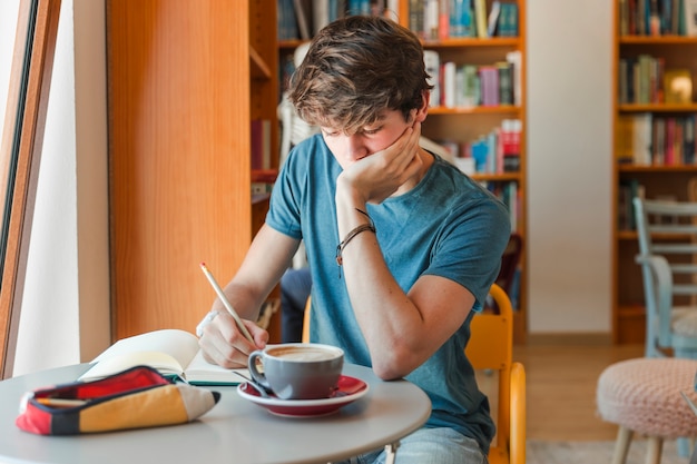 Jugendlich Junge, der Hausarbeit in der Bibliothek tut