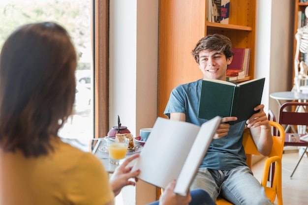 Jugendlich Junge mit dem Buch, das Freundin betrachtet