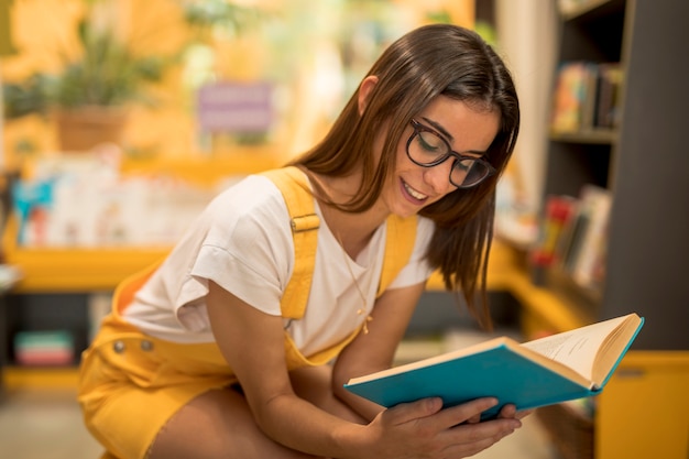 Jugendlich Schulmädchen, das mit Buch sich duckt