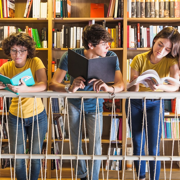 Jugendliche, die nahe Geländer in der Bibliothek lesen