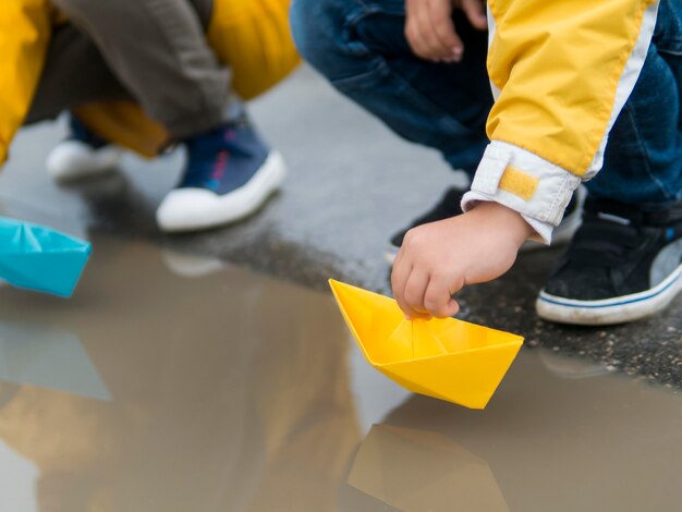 Jugendliche in Regenmänteln, die mit Plastikbooten spielen